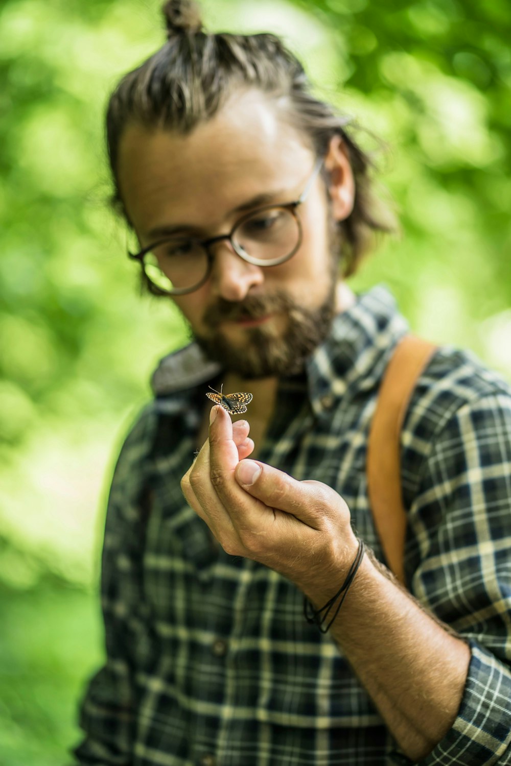 man in black and brown plaid shirt holding brown leaf