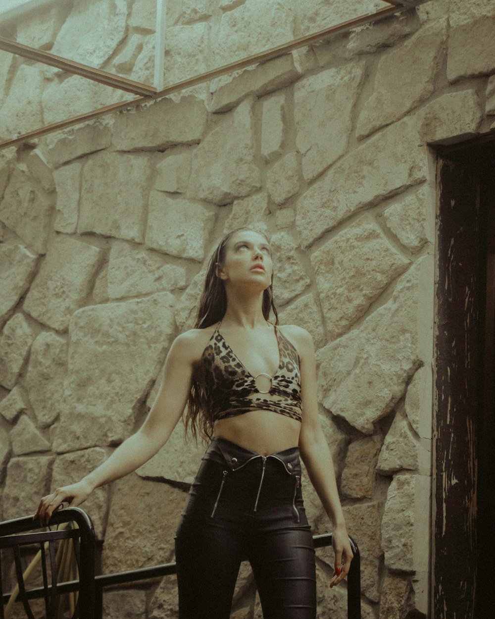 woman in black and brown leopard print brassiere and black skirt standing beside brown wooden door