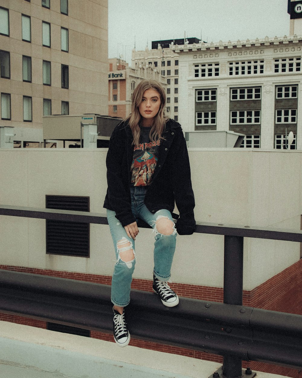 woman in black long sleeve shirt and blue denim shorts sitting on brown wooden bench