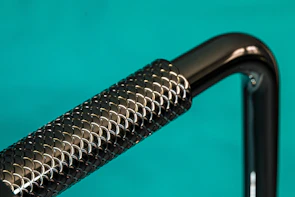 Elegant handcrafted whip with dark chrome handle resting on textured graphite fabric.