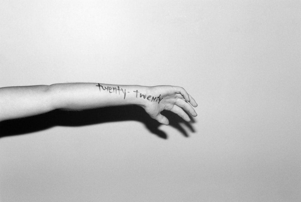 grayscale photo of human hand with tattoo