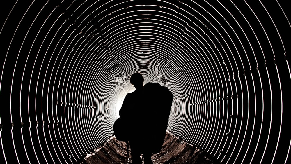 silhouette of person standing on tunnel