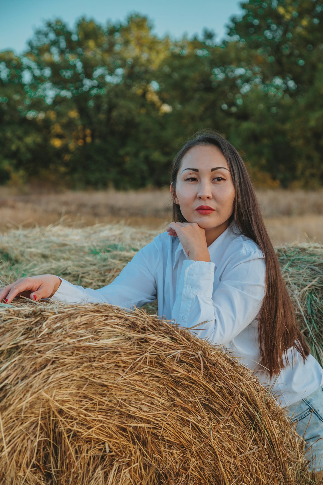 woman in white long sleeve shirt sitting on brown hay