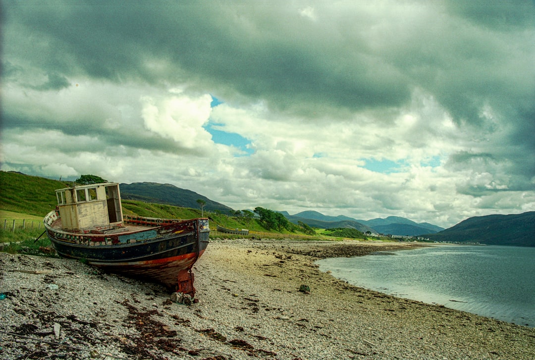 brown boat on seashore under cloudy sky during daytime