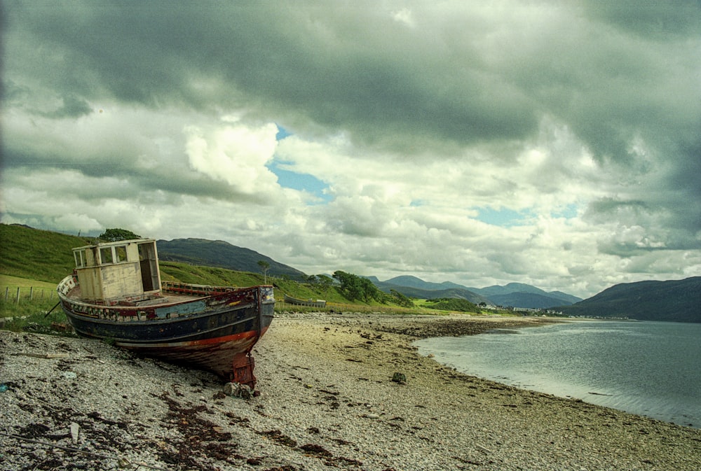brown boat on seashore under cloudy sky during daytime