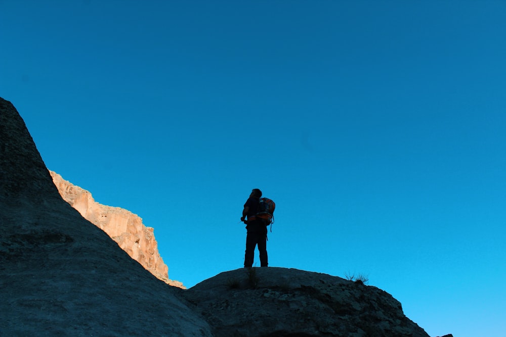 man in black jacket standing on brown rock formation during daytime