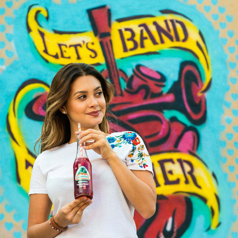 woman in white crew neck t-shirt holding bottle