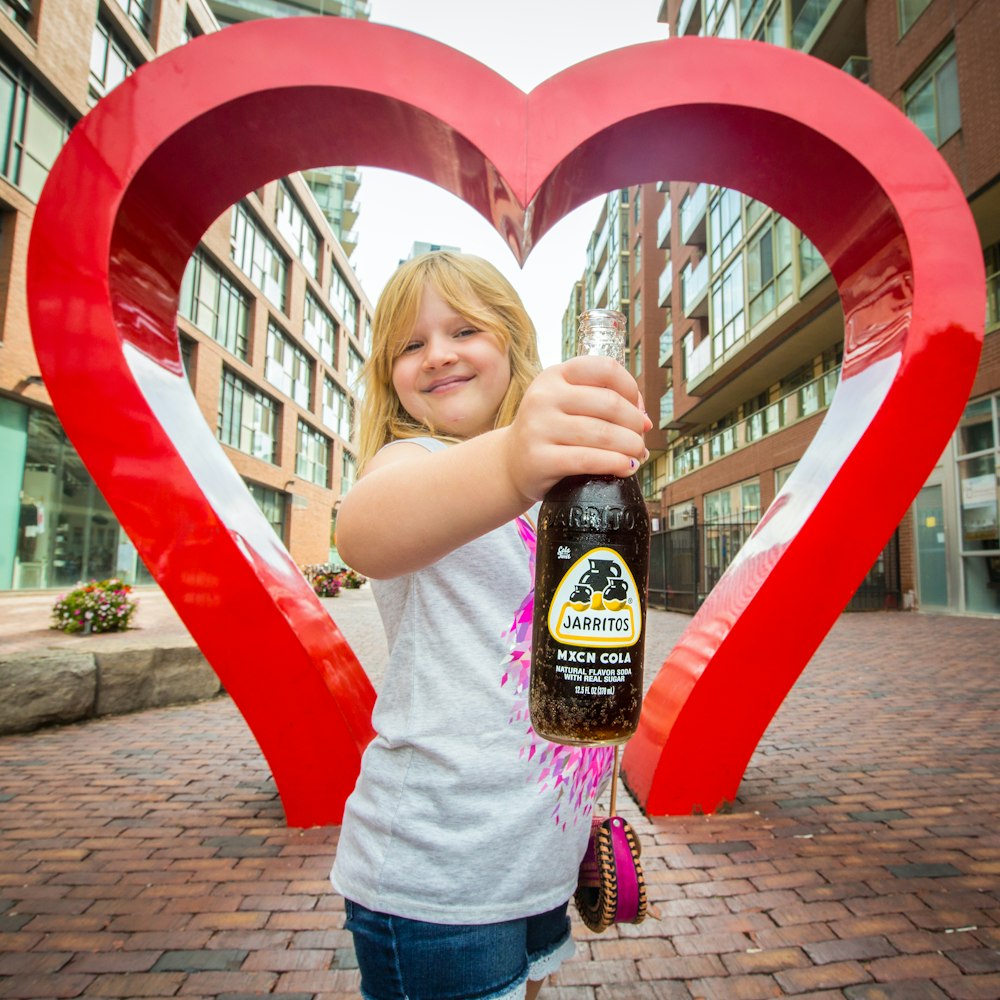 girl in pink t-shirt holding black bottle