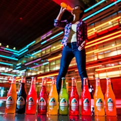 Young person happily drinking from a sleek premium water bottle outdoors in vibrant city colors.
