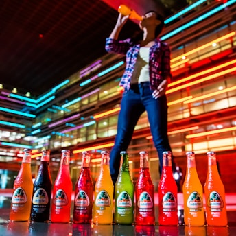 Young person happily drinking from a sleek premium water bottle outdoors in vibrant city colors.