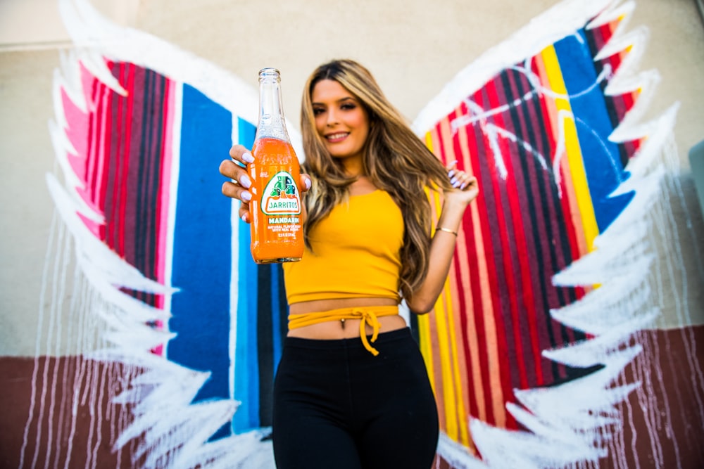 woman in yellow tank top holding bottle