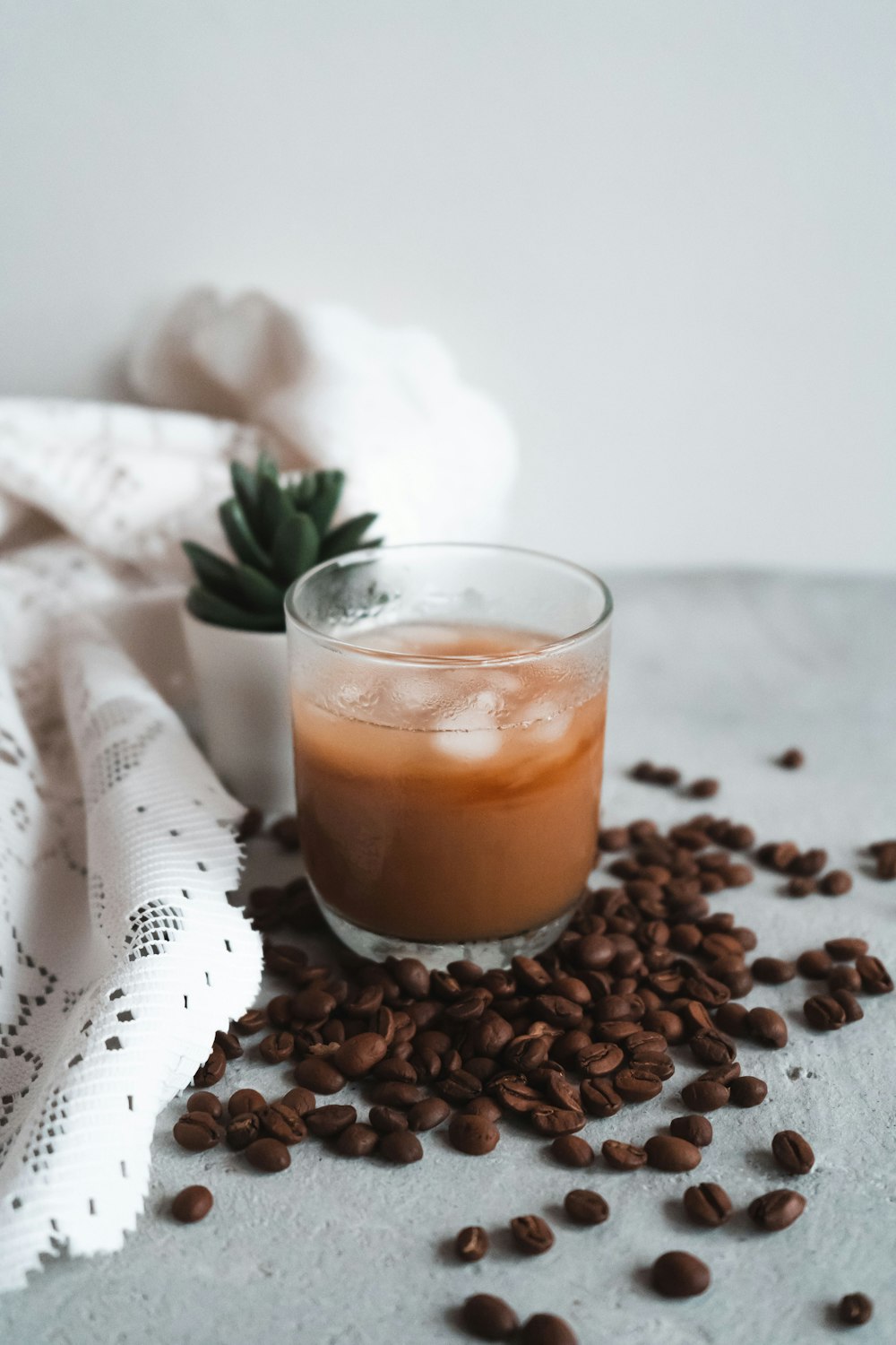 clear drinking glass with brown liquid on white textile