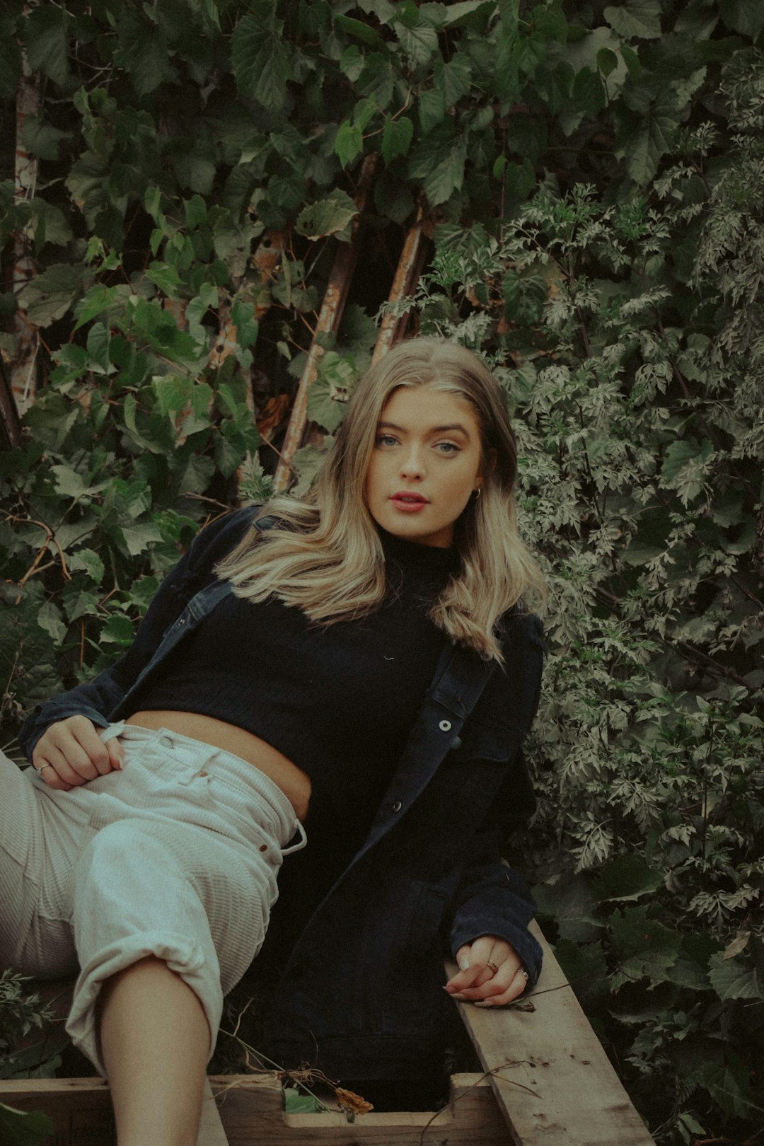 woman in black jacket and gray denim jeans sitting on gray rock