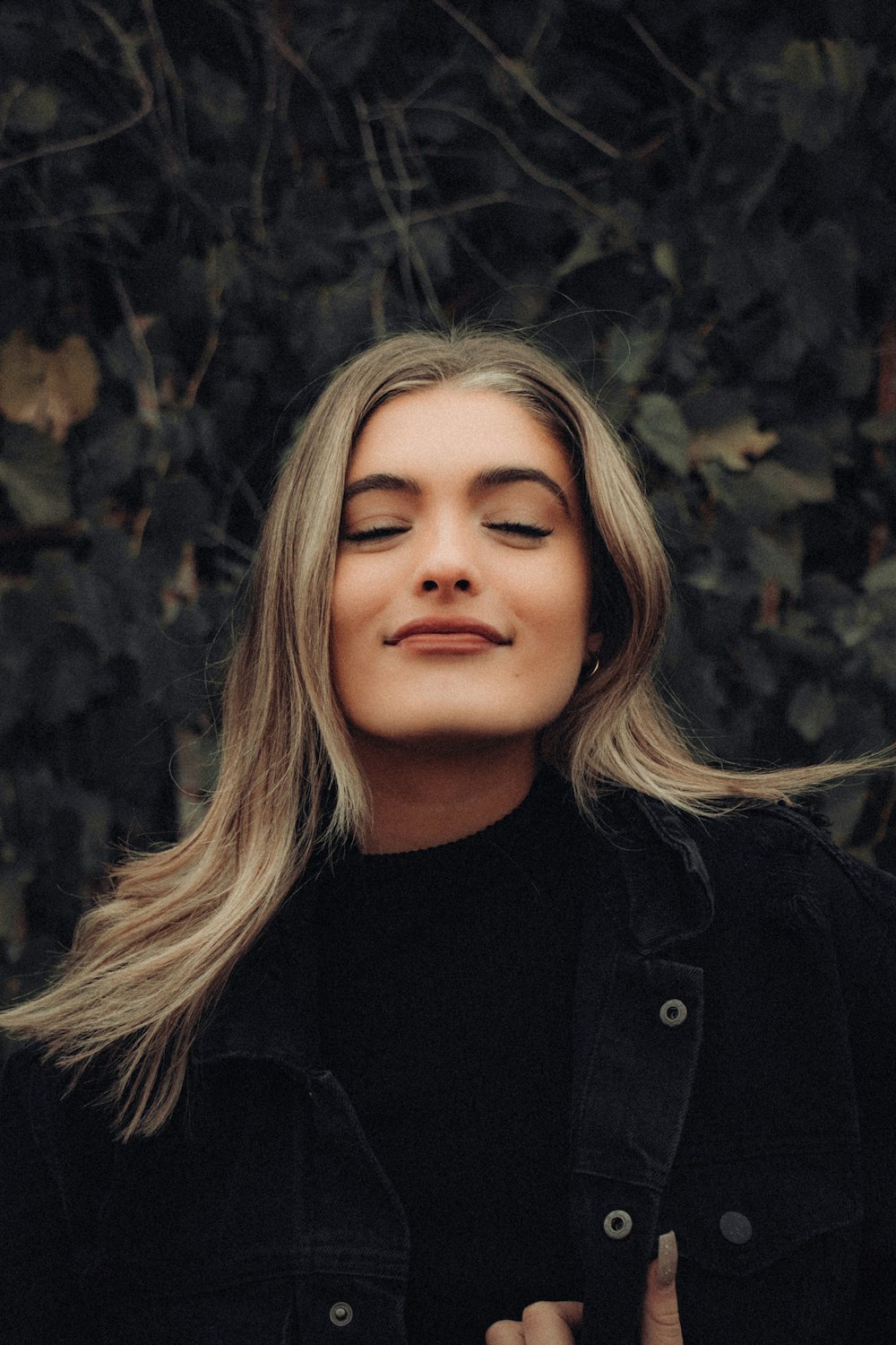 fille en veste noire debout près de feuilles brunes