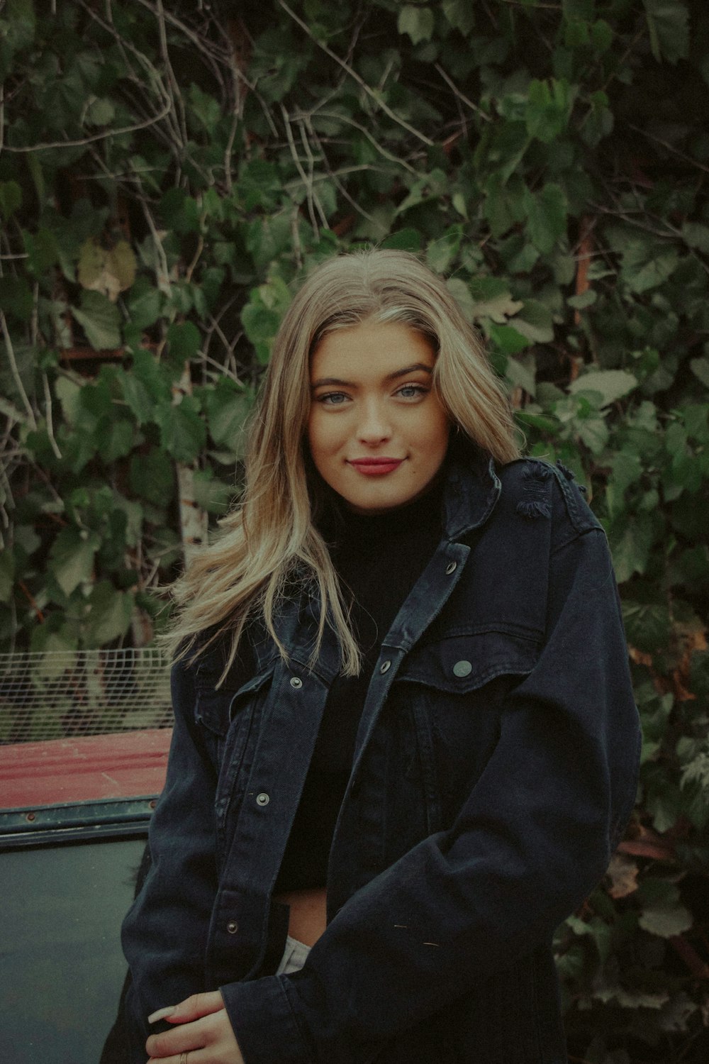 woman in black jacket sitting on red bench