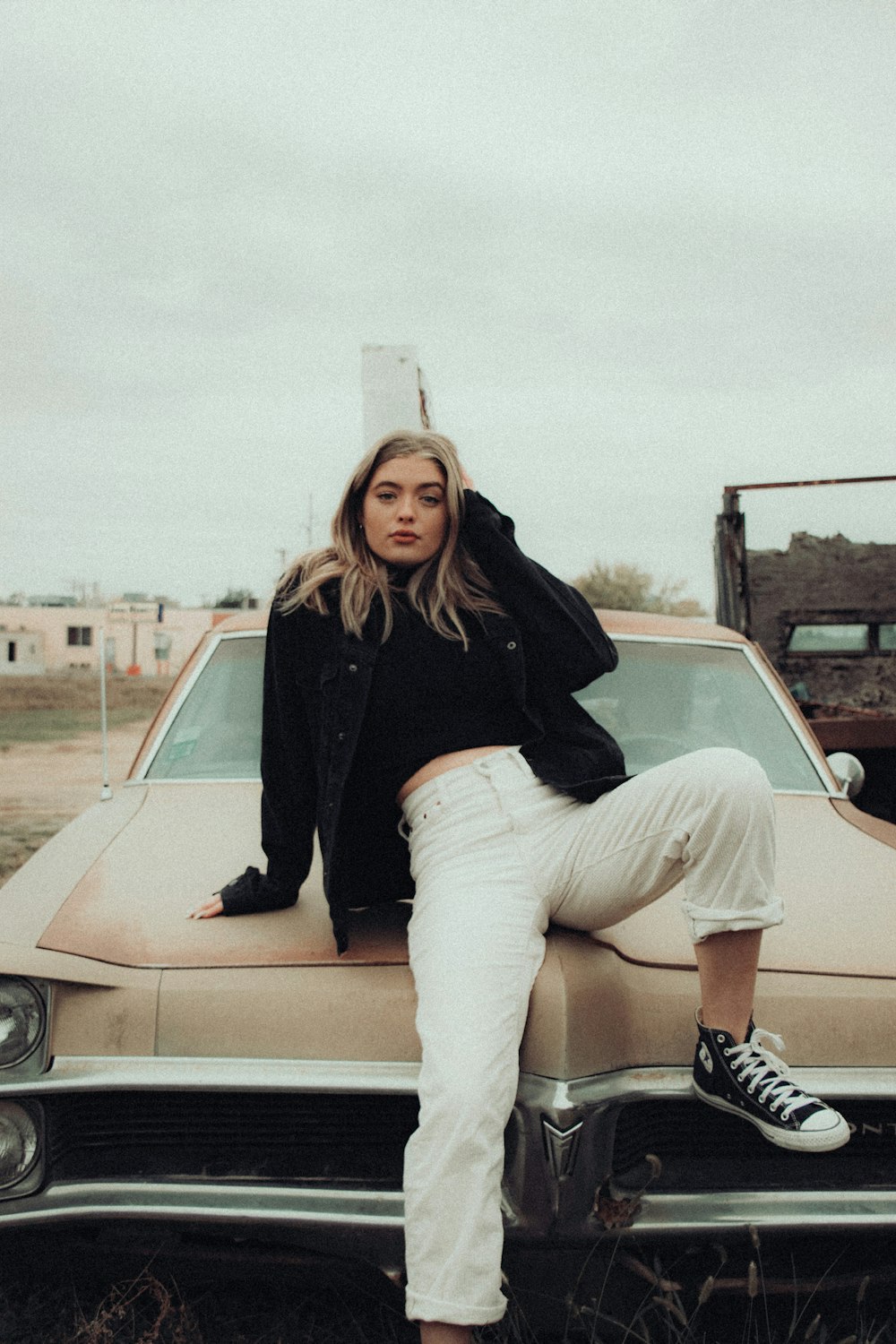 woman in black long sleeve shirt and white skirt sitting on white car
