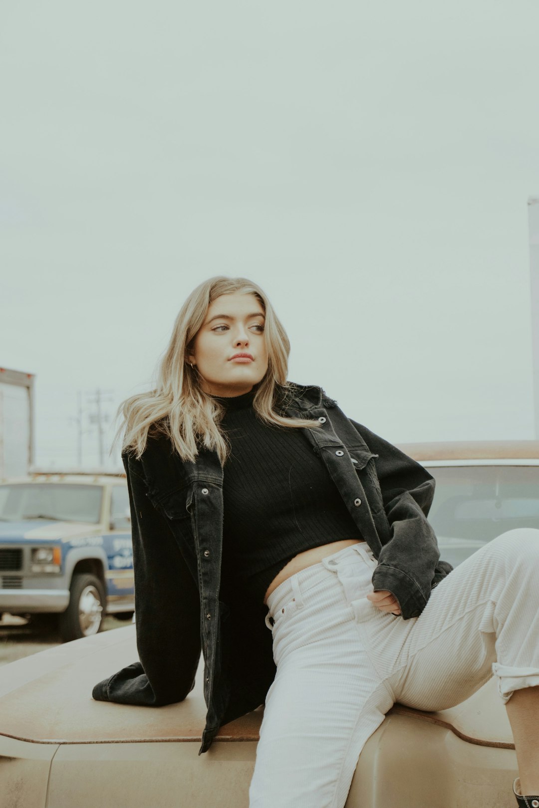 woman in black jacket and white pants sitting on concrete bench