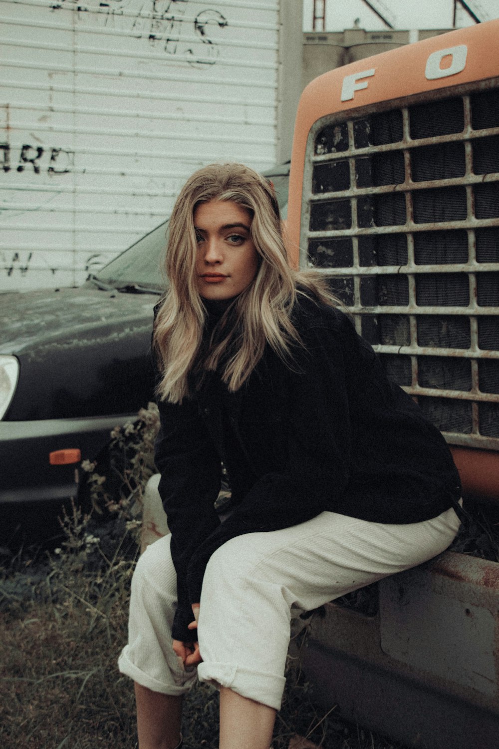 woman in black sweater and white pants sitting on brown concrete bench