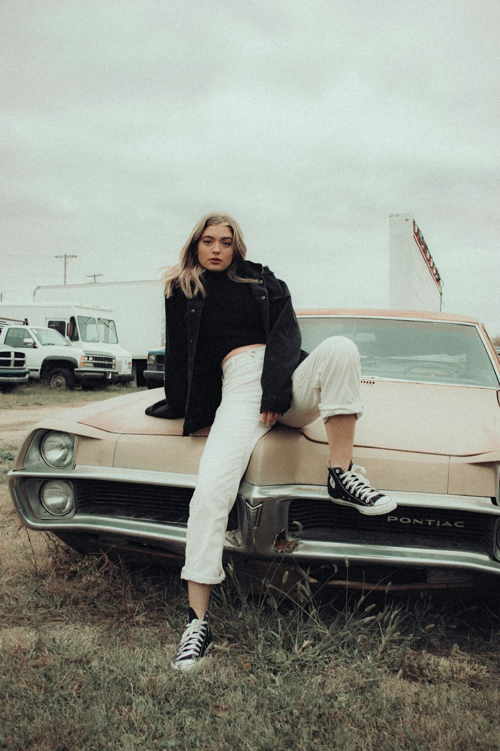 woman in black long sleeve shirt and white skirt sitting on white car