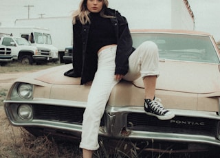 woman in black long sleeve shirt and white skirt sitting on white car