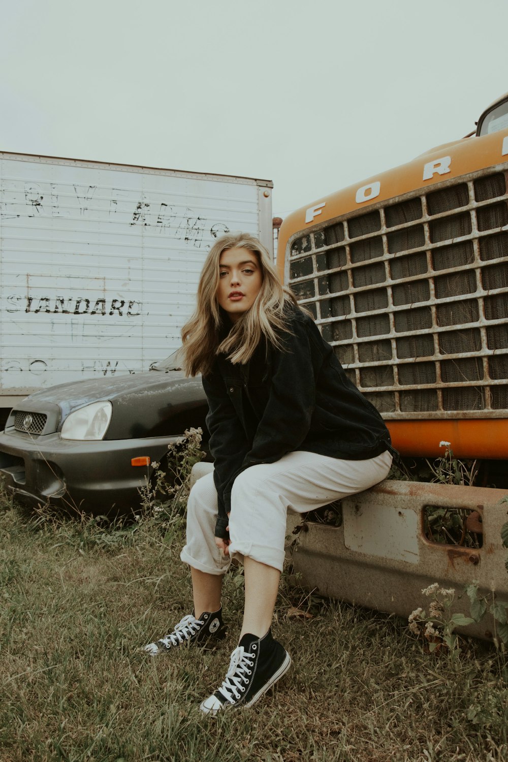 woman in black long sleeve shirt and white pants sitting on white car