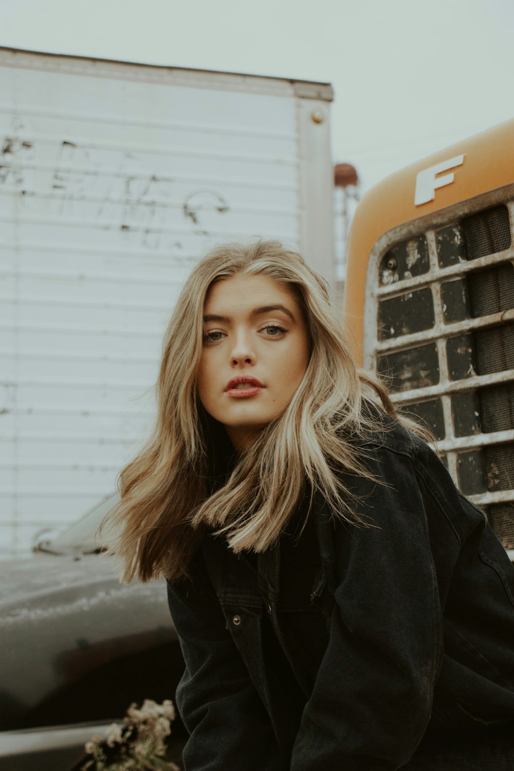 woman in black jacket standing near orange and white bus during daytime