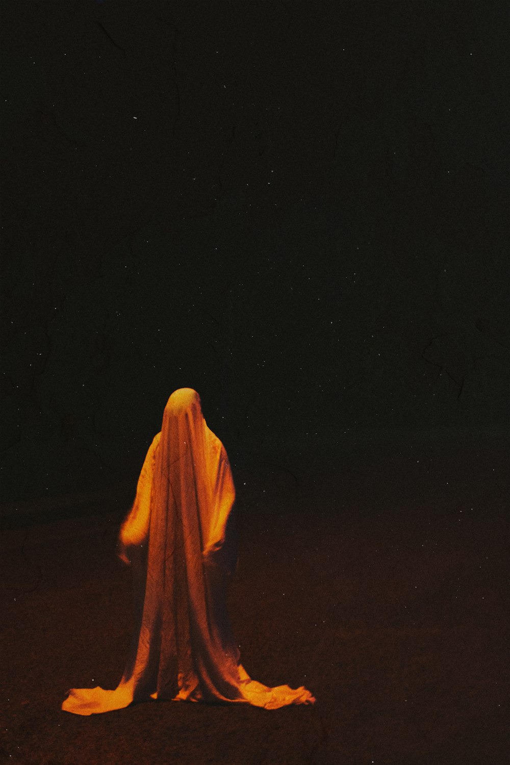 노란 히잡을 쓴 사람이 밤에 갈색 들판에 서 있는 사람