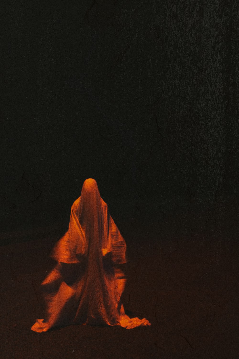 Mujer con hiyab naranja de pie sobre una superficie negra