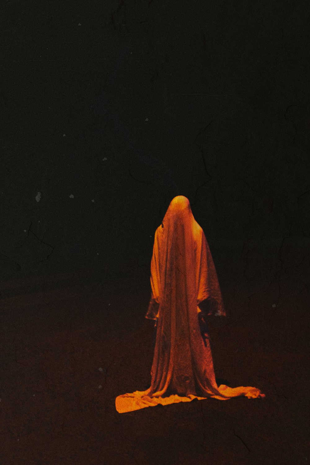 Mujer con hiyab marrón de pie sobre una superficie negra