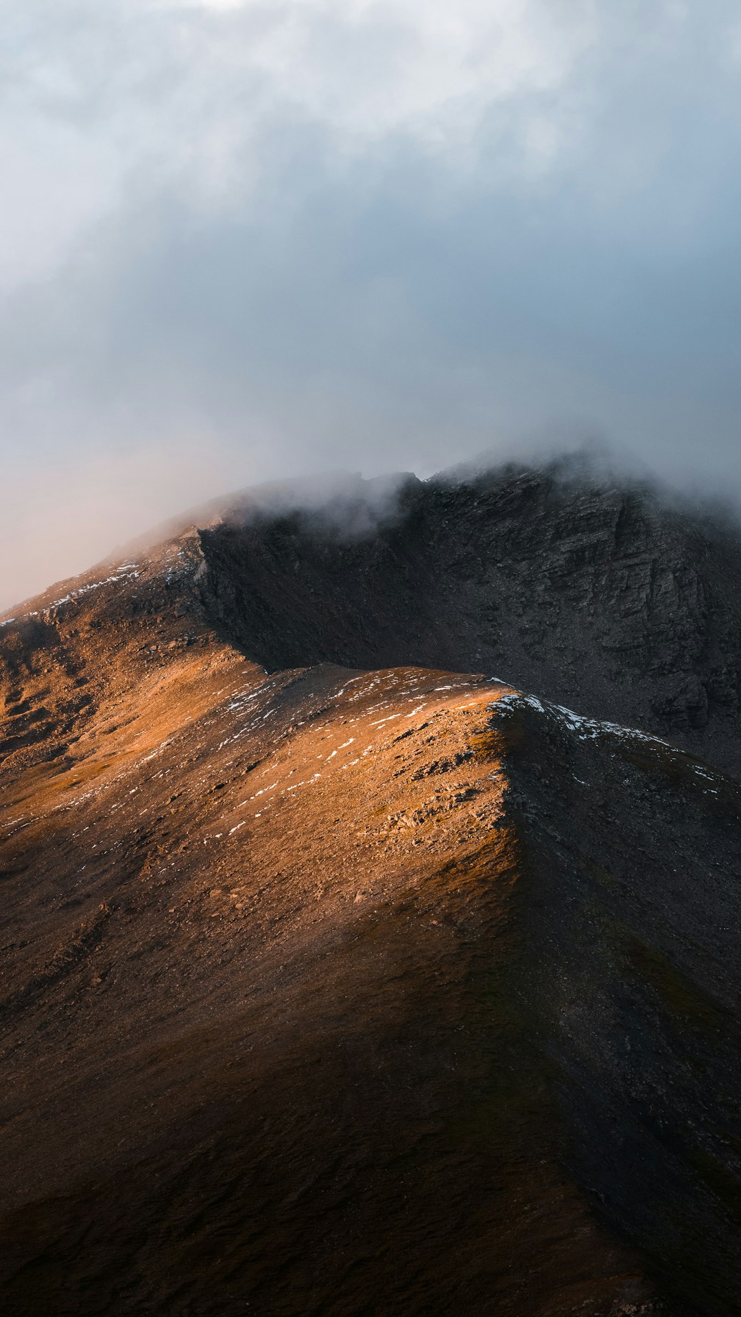 brown and black mountain under white clouds