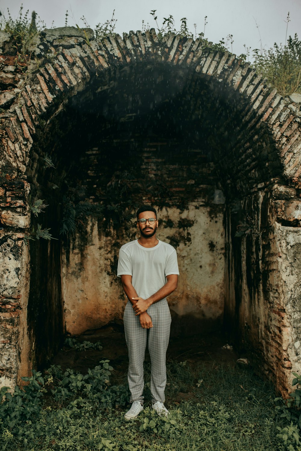 man in white crew neck t-shirt and gray pants standing in tunnel
