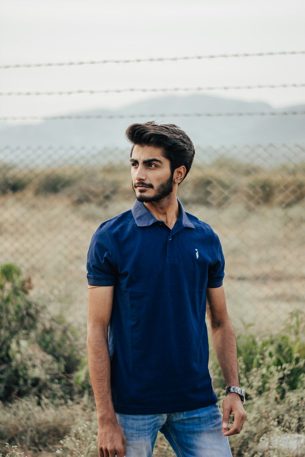 man in blue polo shirt standing on green grass field during daytime