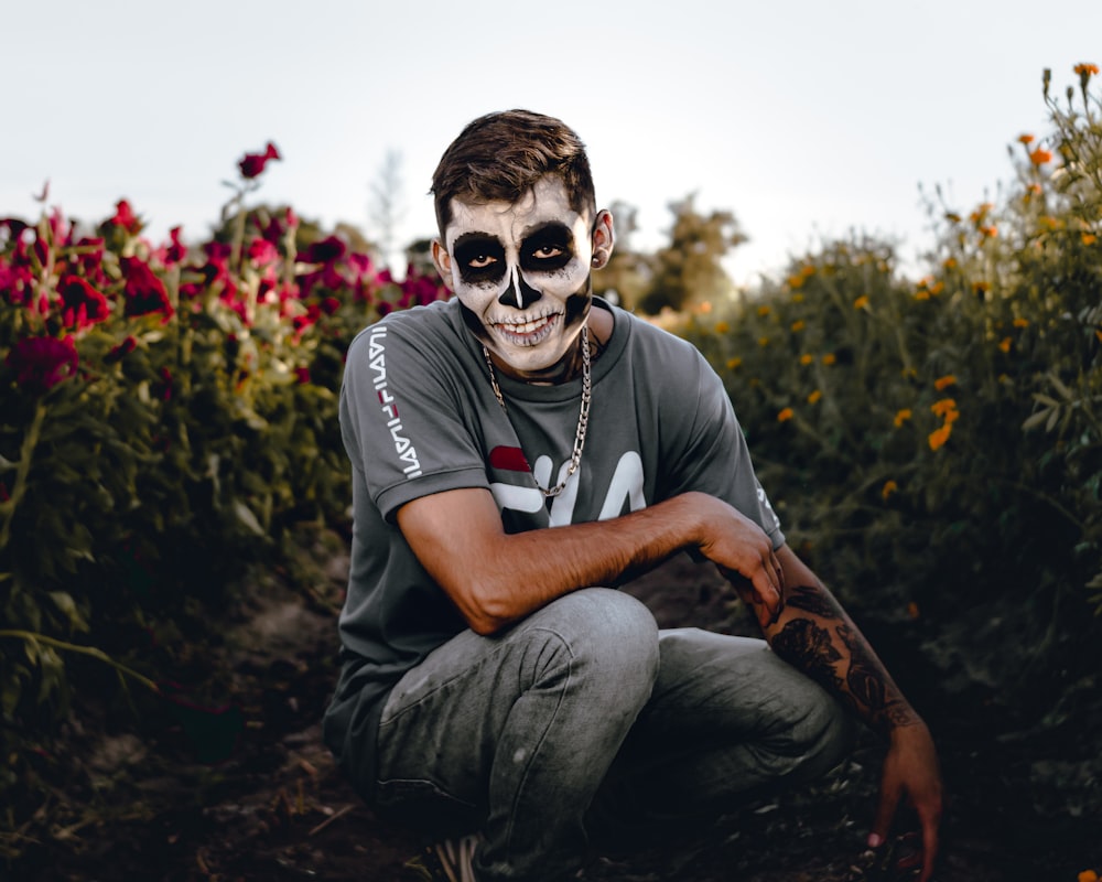 man in black and white crew neck t-shirt and gray pants sitting on ground during