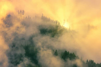 Sunlight piercing through fog over a rugged ridge on the Netravati trek.