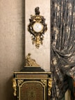 Close-up of elegant vintage clock and ornate picture frames on a polished wooden dresser.