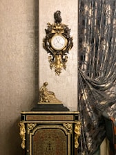 Close-up of elegant vintage clock and ornate picture frames on a polished wooden dresser.