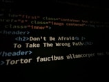 A close-up shot of a computer screen displaying HTML and CSS code. Part of the code reads 'Don't Be Afraid To Take The Wrong Path' in an h2 header tag. Other code elements using classes and tags are visible around the center message.