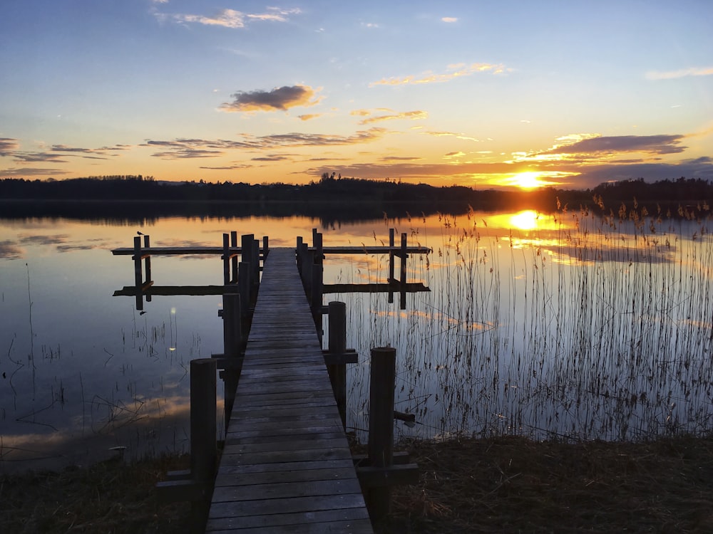 brown wooden dock on lake during sunset