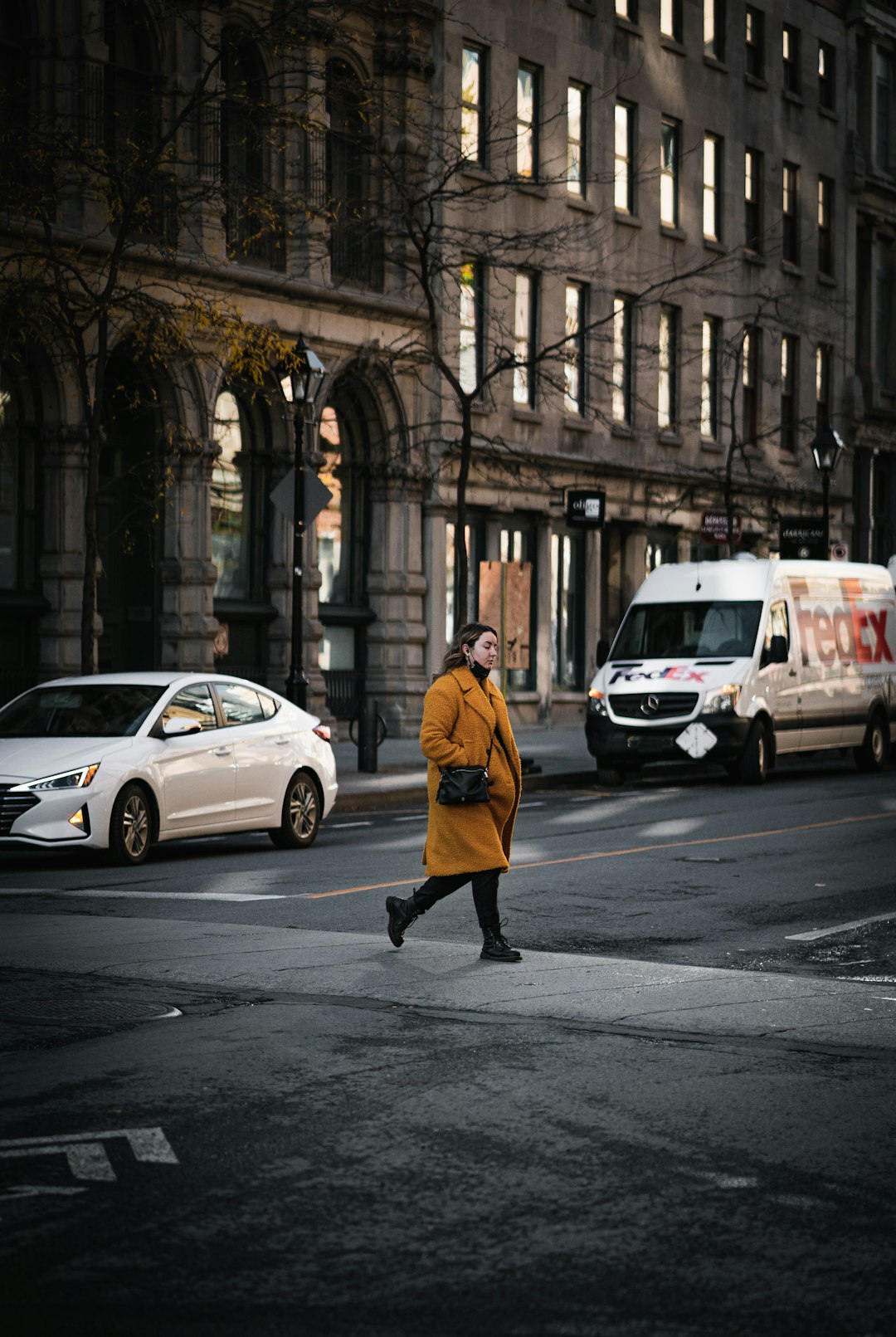 man in yellow jacket walking on sidewalk near white suv during daytime