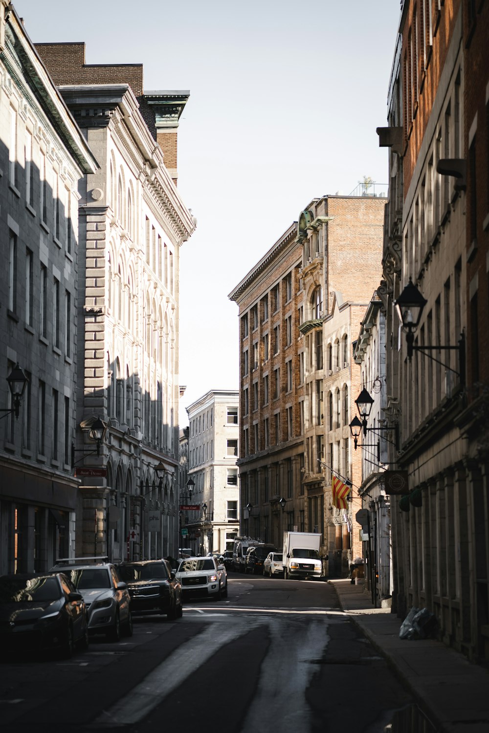 cars parked on side of the road in between buildings during daytime