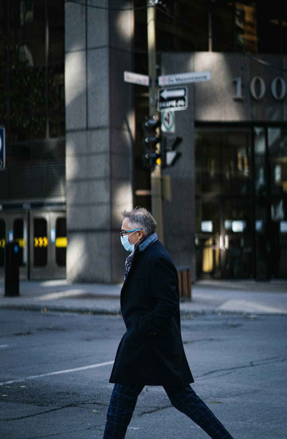 man in black jacket wearing white and blue knit cap standing near building during daytime