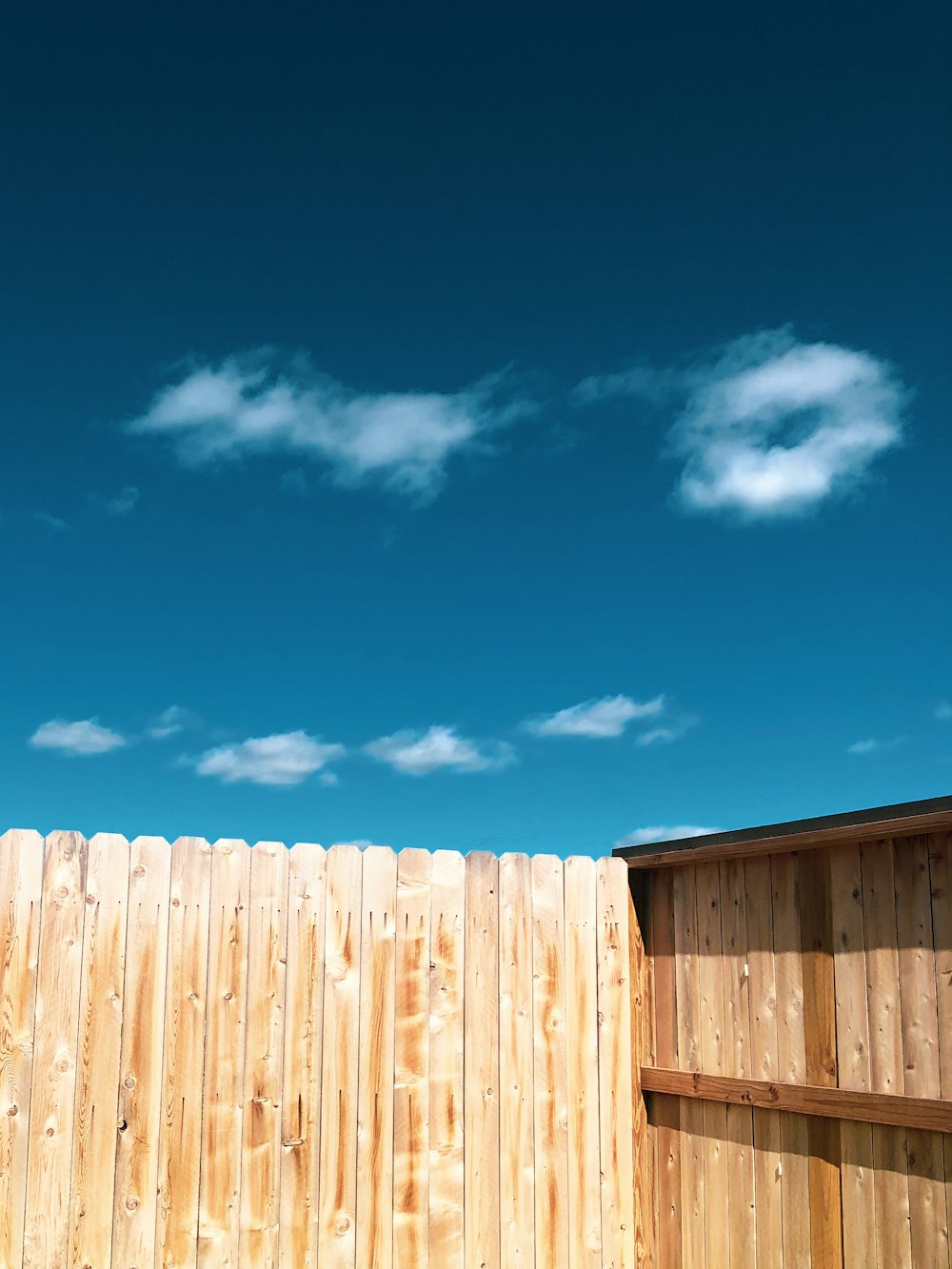 New cedar privacy fence against a clear blue Tulsa sky