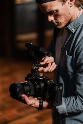 A filmmaker adjusting a camera on a tripod during a shoot.