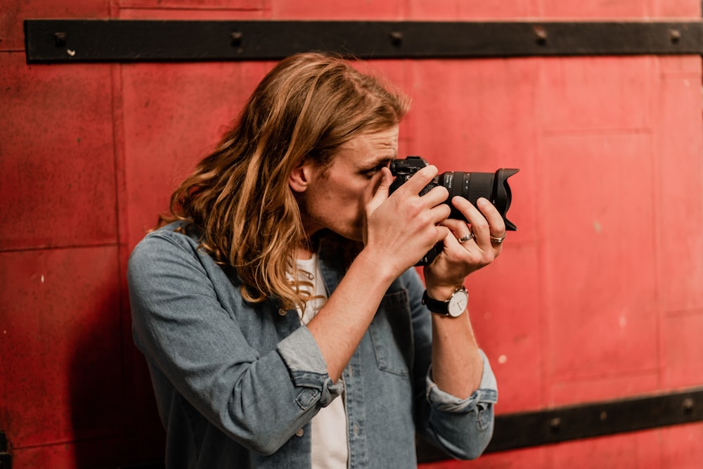 woman in blue denim jacket holding black dslr camera