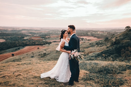 man and woman kissing on brown grass field during daytime