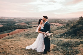 man and woman kissing on brown grass field during daytime