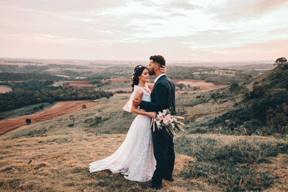 man and woman kissing on brown grass field during daytime