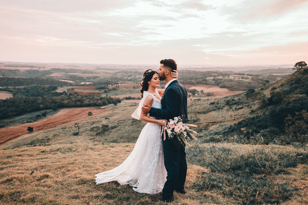 homem e mulher que se beijam no campo de grama marrom durante o dia