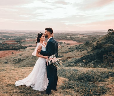 man and woman kissing on brown grass field during daytime