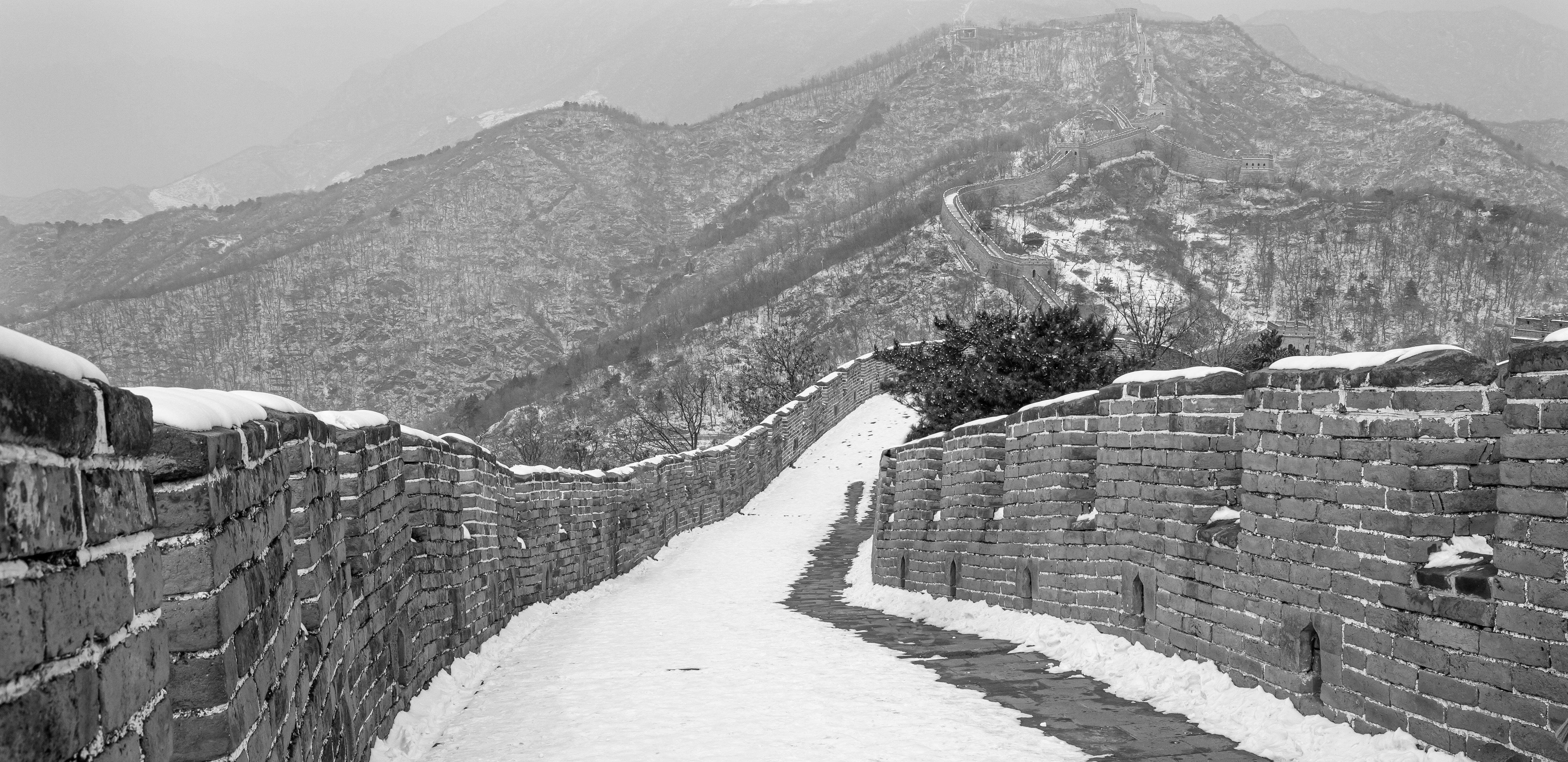 Hiker walking along Great Wall path with panoramic mountain backdrop showing the journey concept